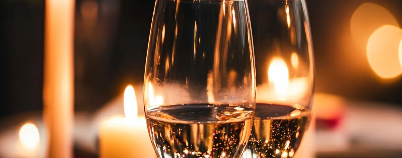 två glas mousserande vin, tända stearinljus