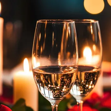 två glas mousserande vin, tända stearinljus