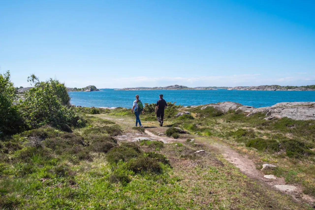 två personer vandrar på stig vid havet