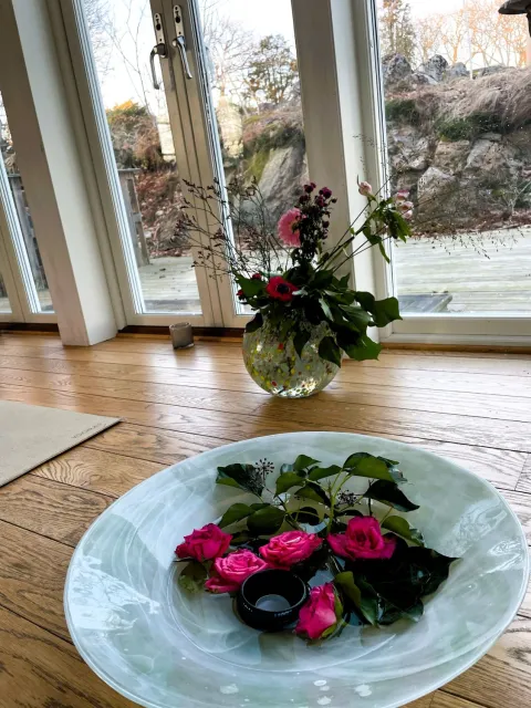 fat med blommor och blad framför fönster