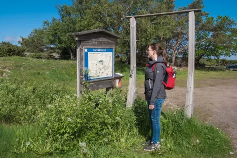 kvinna läser naturreservat skylt