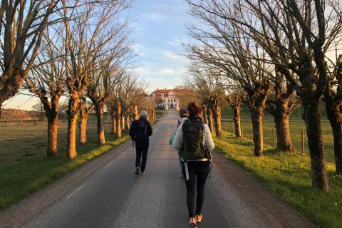 tre personer vandrar mot herrgårdsbyggnad