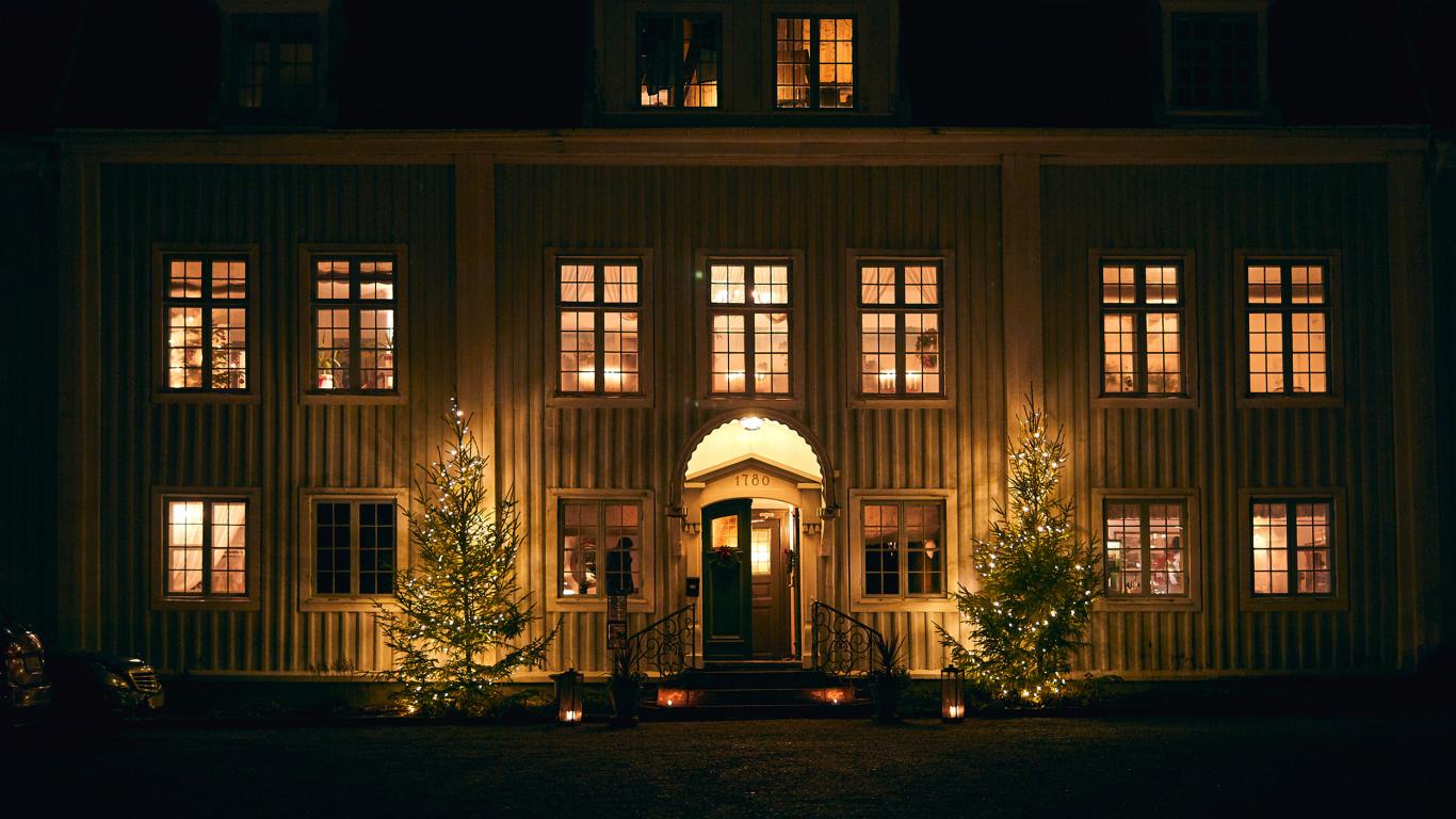 Tofta Herrgård med juleljus och julgranar ute